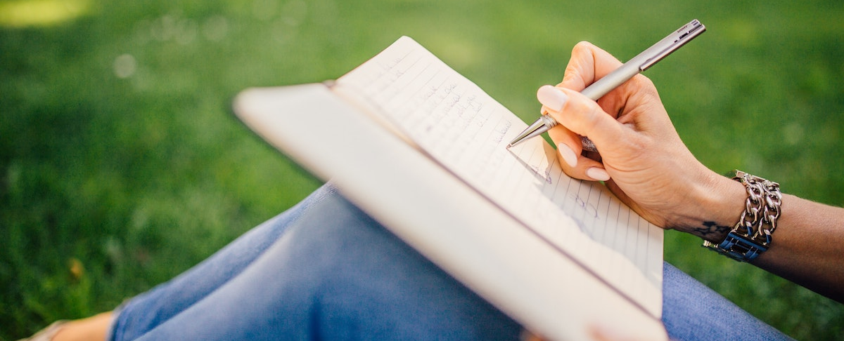 woman writing in journal outside